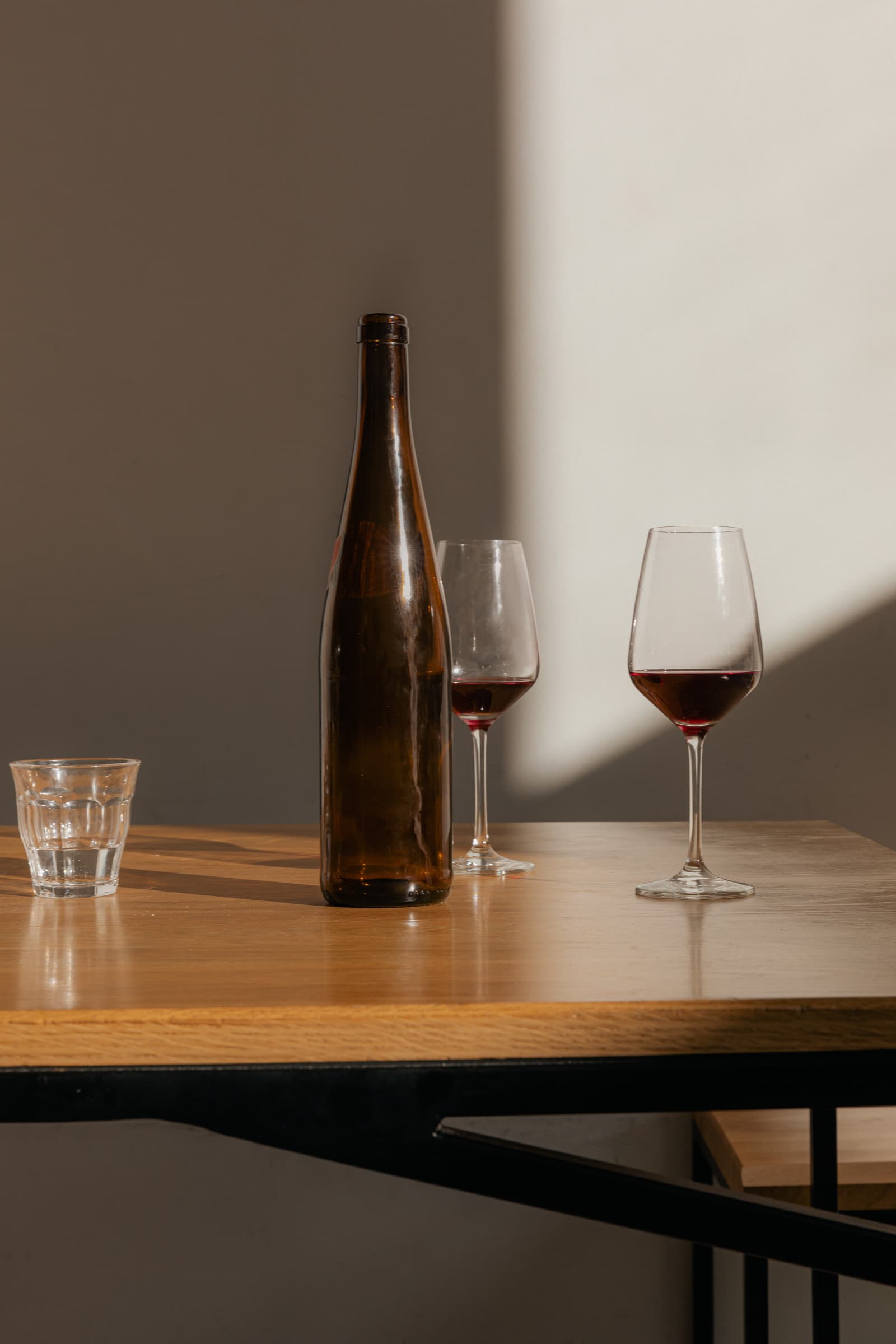 Een fles wijn en twee glazen op een lege houten tafel