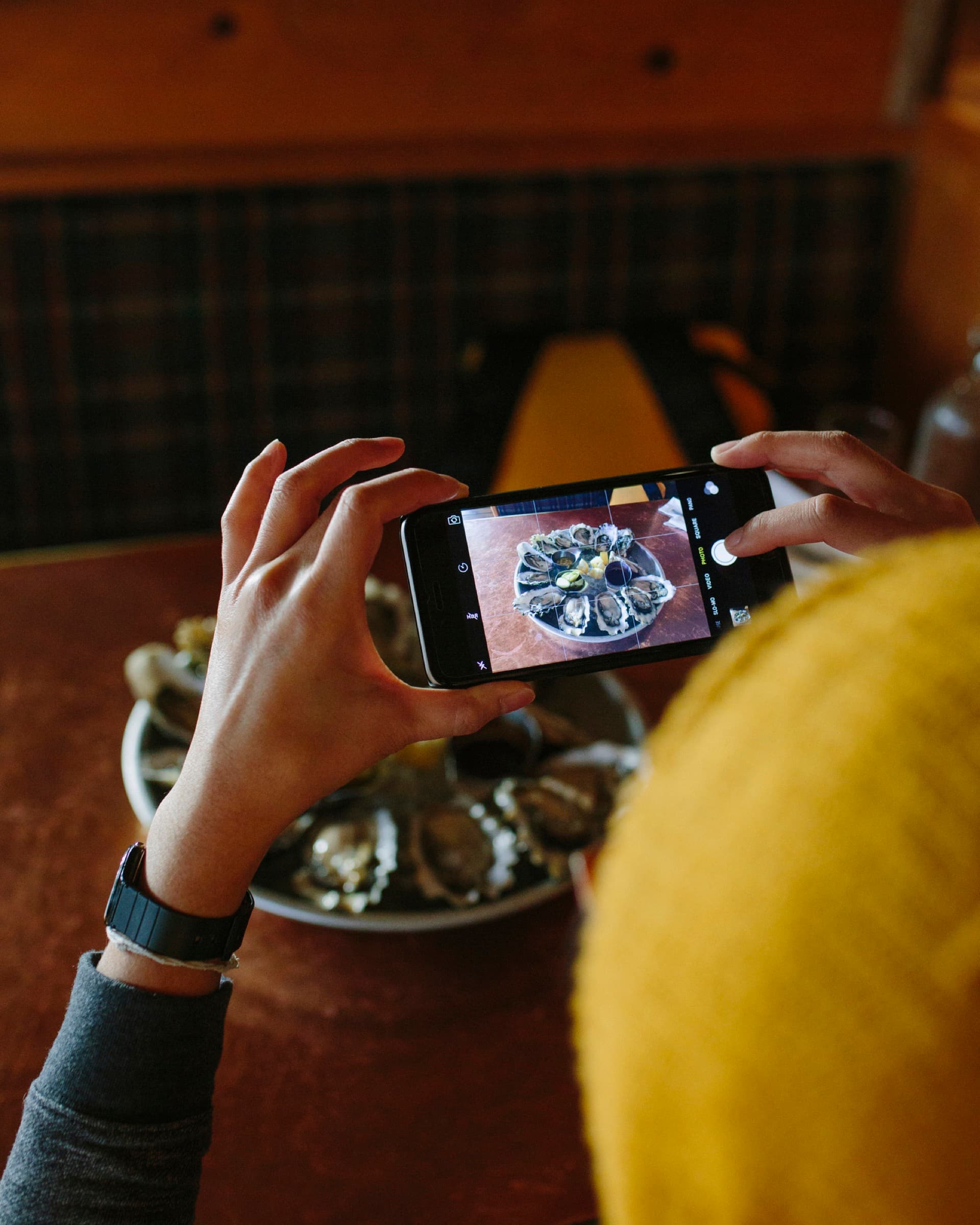 Iemand fotografeert een schaal oesters met een telefoon