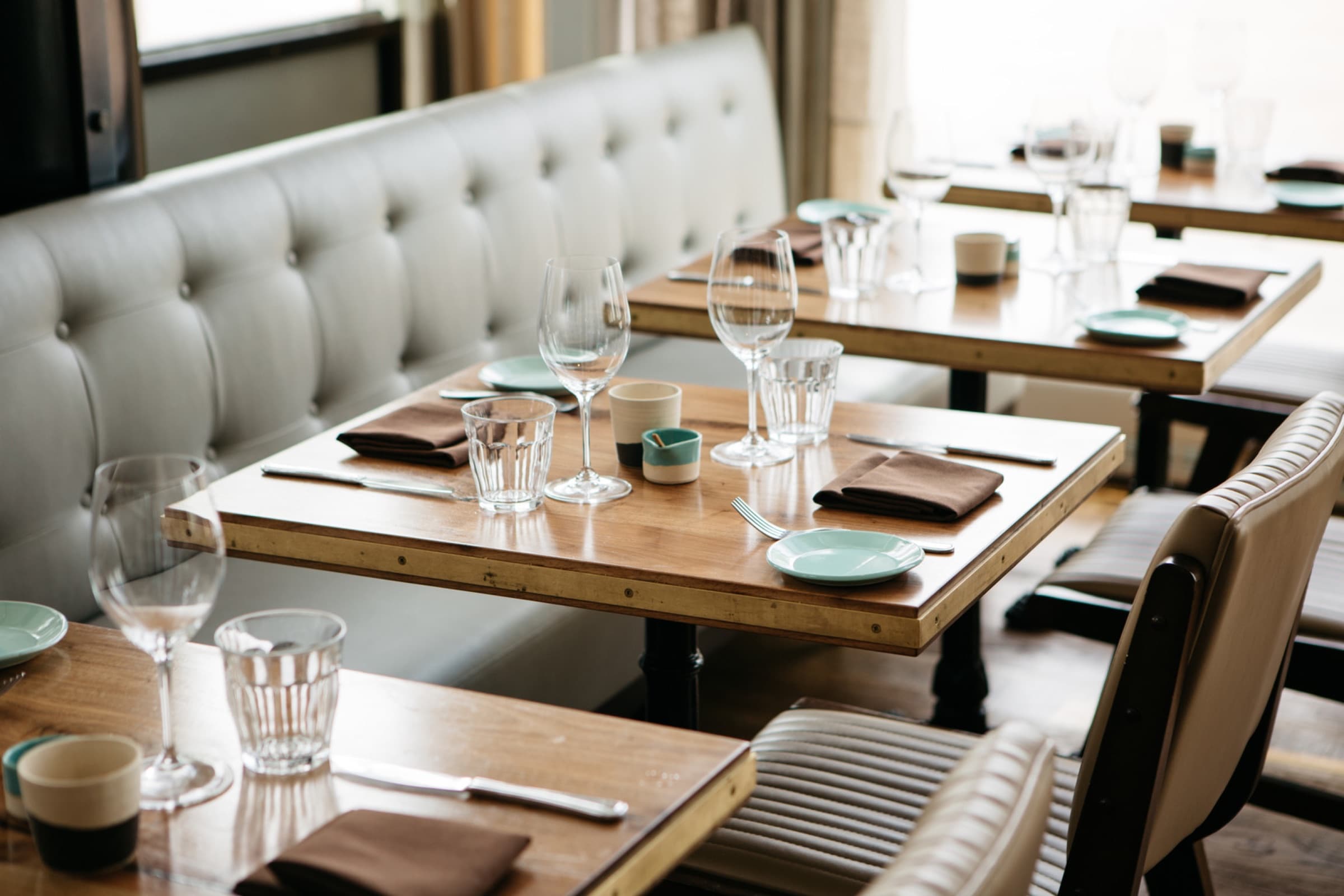 Gedekte tafels met glazen en servetten in een leeg restaurant