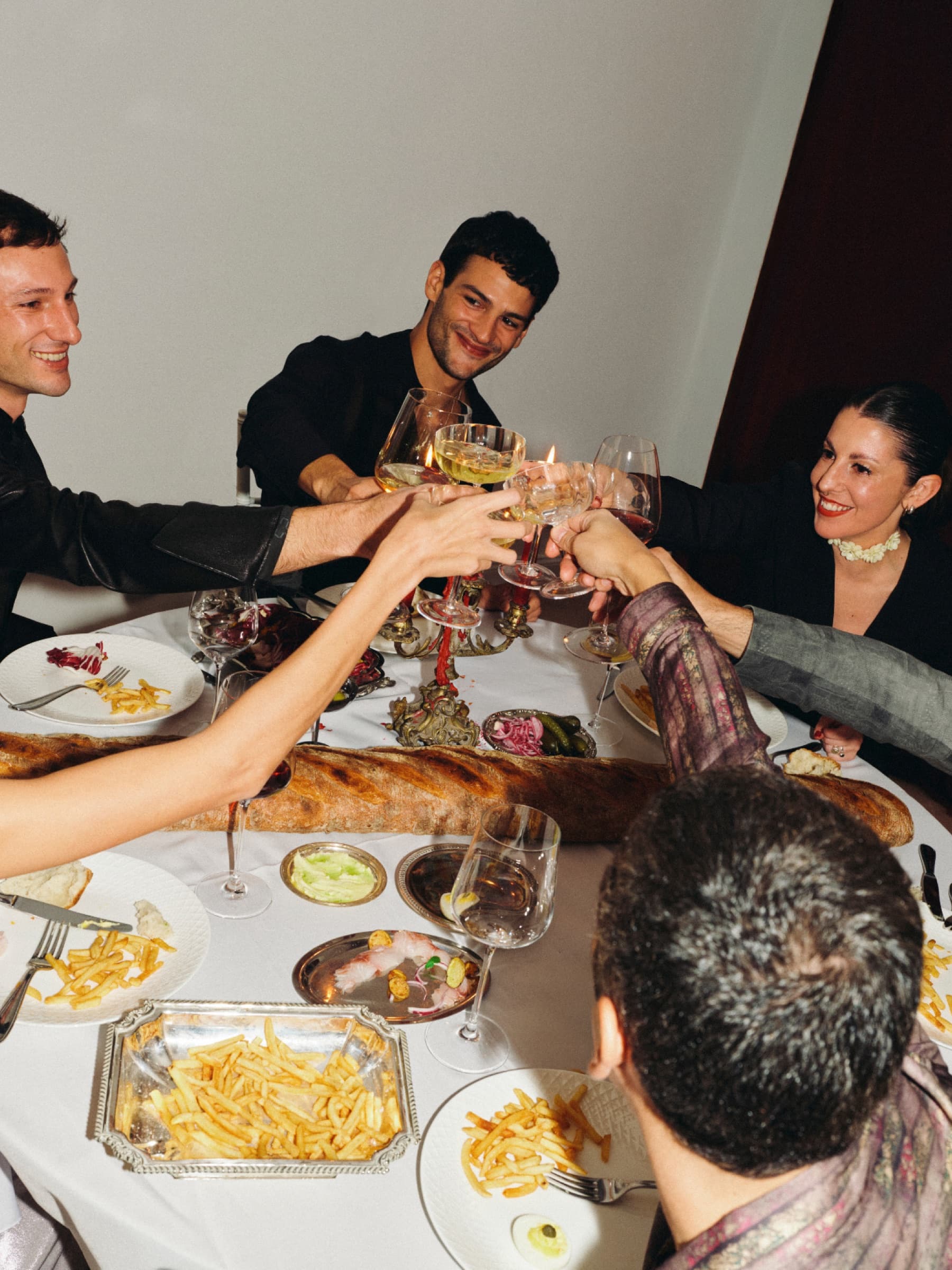 Een groep vrienden proost aan een ronde tafel