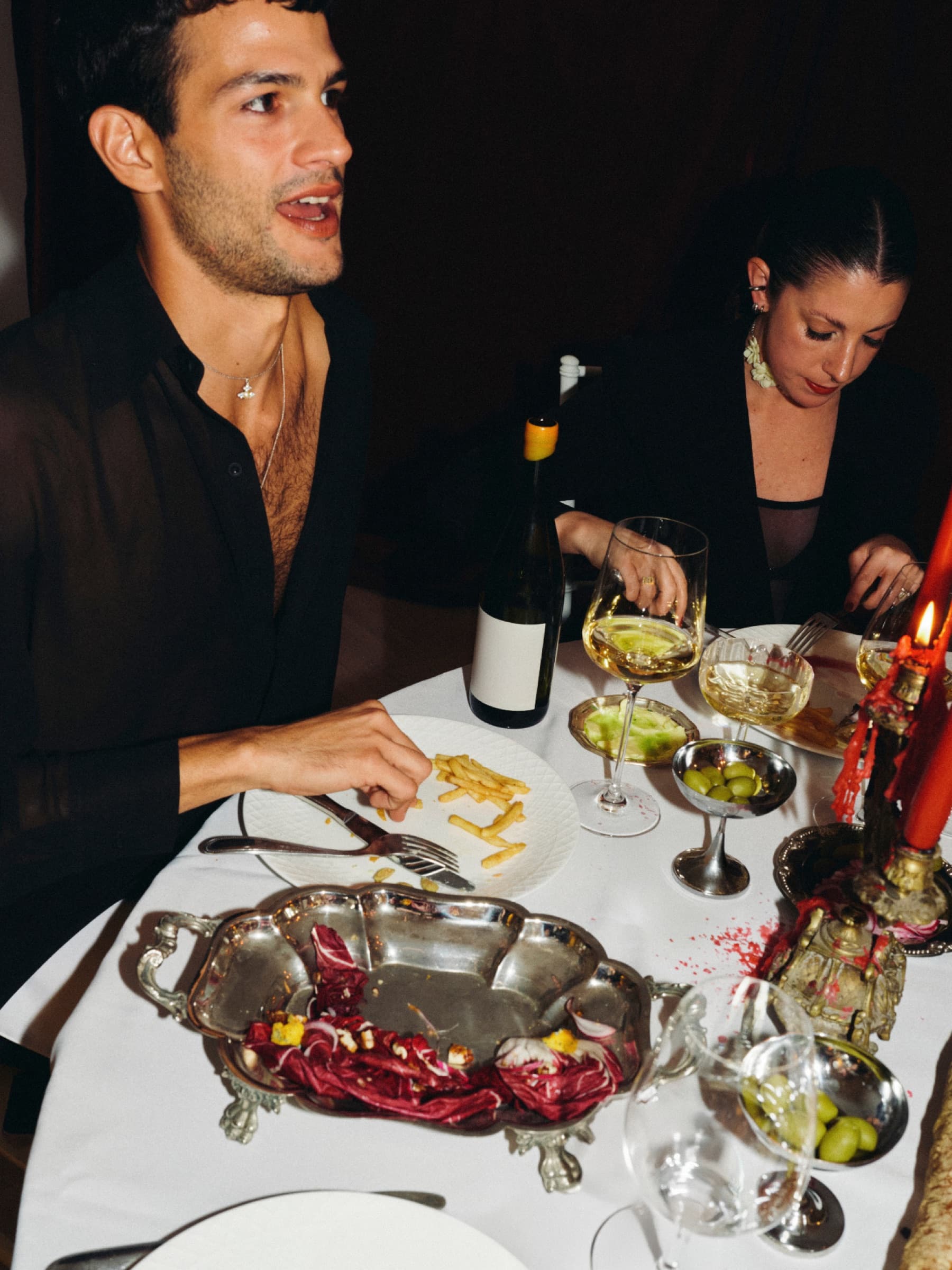 Een man en een vrouw dineren bij kaarslicht aan een gedekte tafel