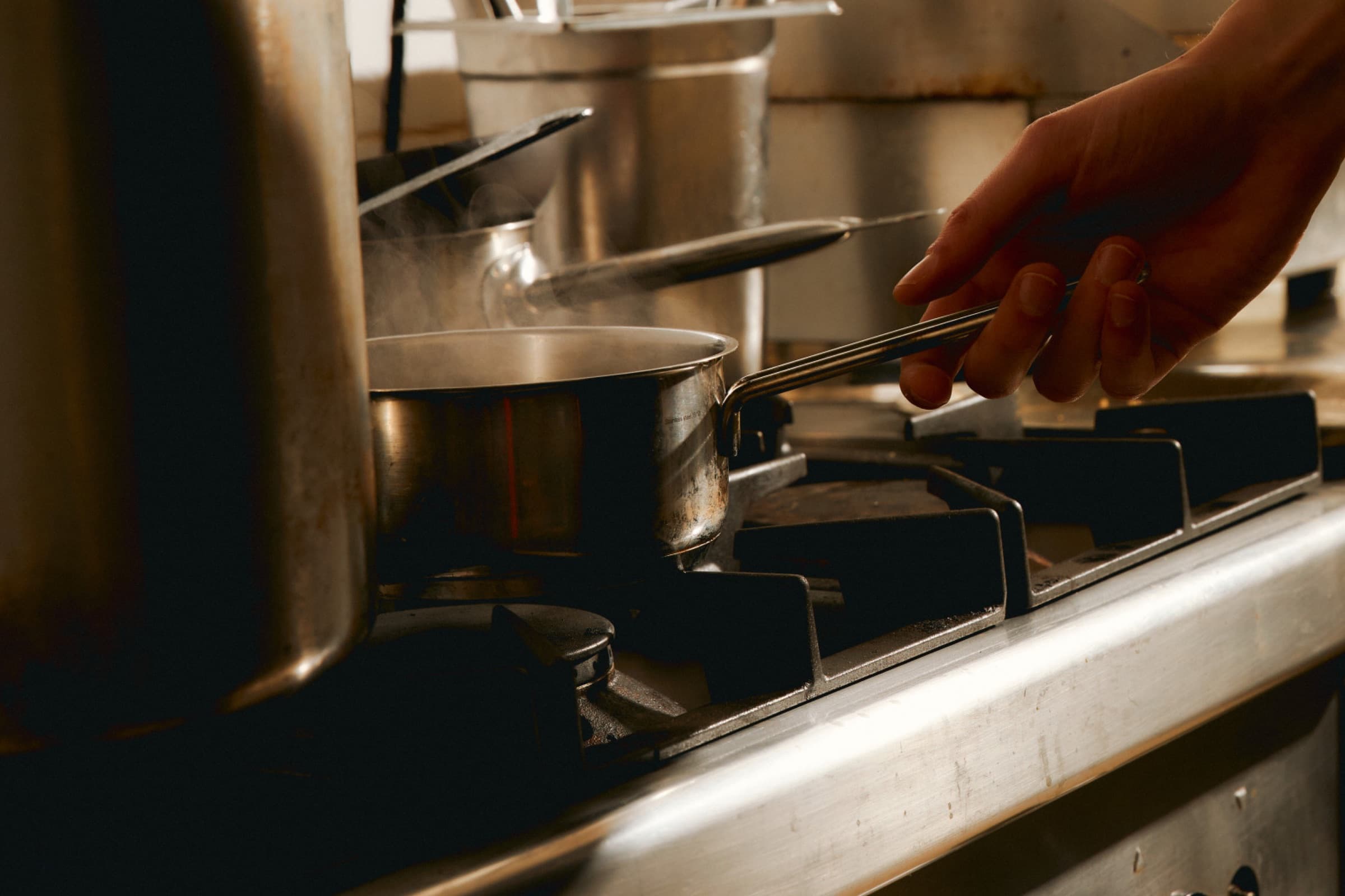 Pannen staan te dampen op het fornuis in een restaurantkeuken