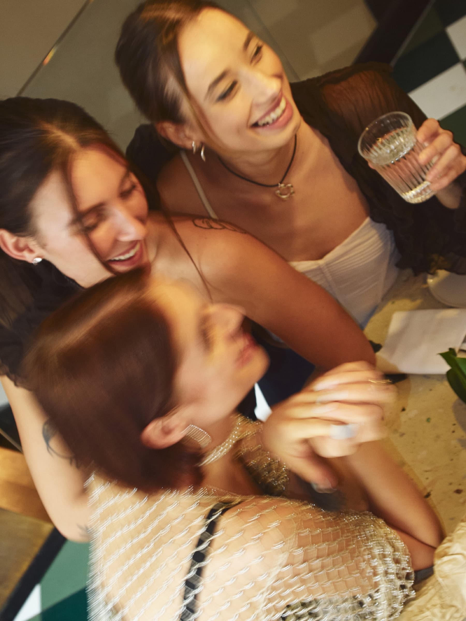 Drie vriendinnen lachen samen aan tafel